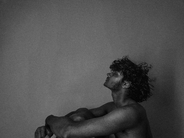 a shirtless man sitting on a toilet in a bathroom