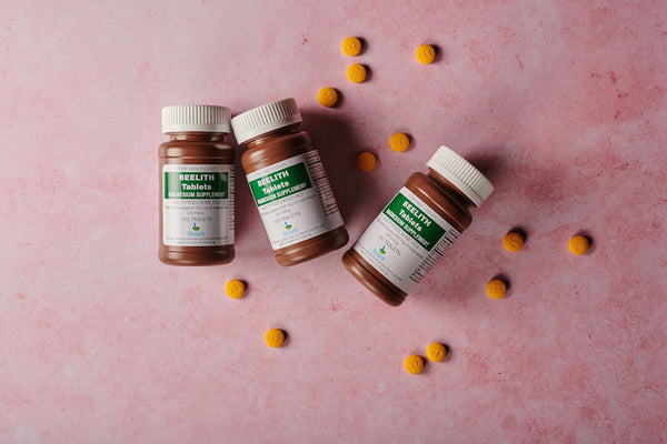 three bottles of vitamins on a pink surface