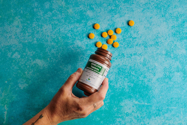 a hand holding a bottle of vitamin pills