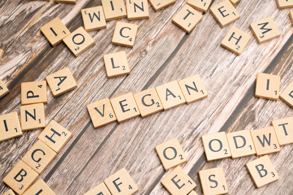 scrabble tiles spelling the word vegan on a wooden surface