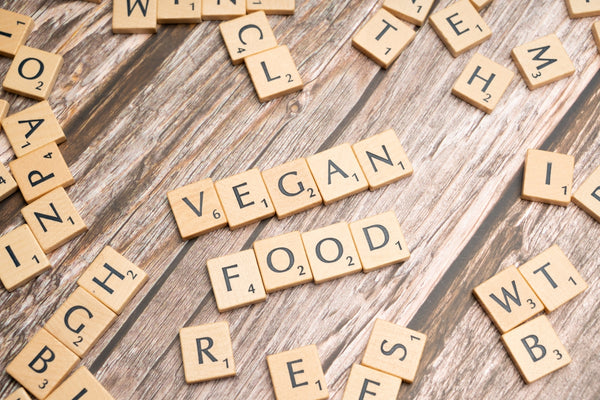 a wooden table topped with scrabble tiles spelling vegan food