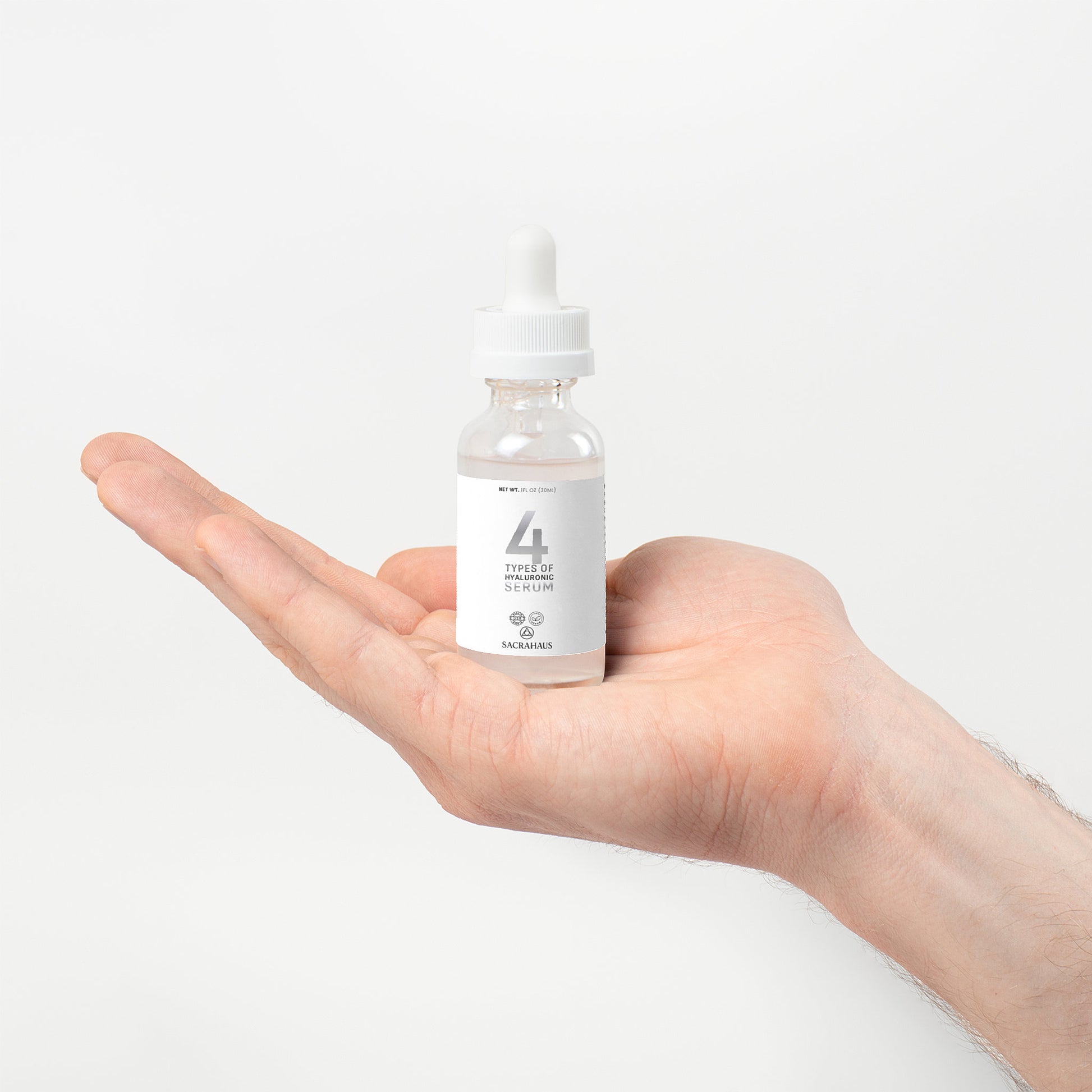 SACRAHAUS vegan hyaluronic acid serum in a dropper bottle held in a hand for facial care
