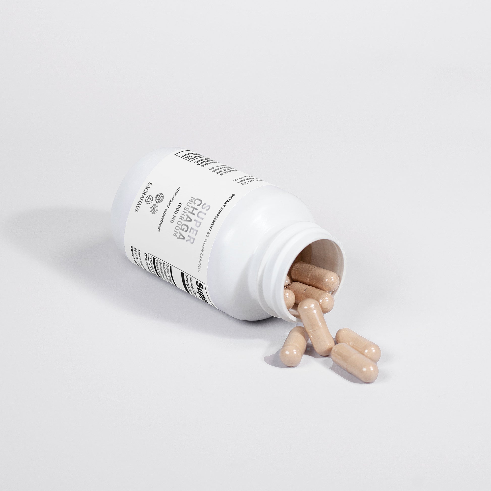 SACRAHAUS chaga mushroom supplement in a white bottle with capsules spilling out