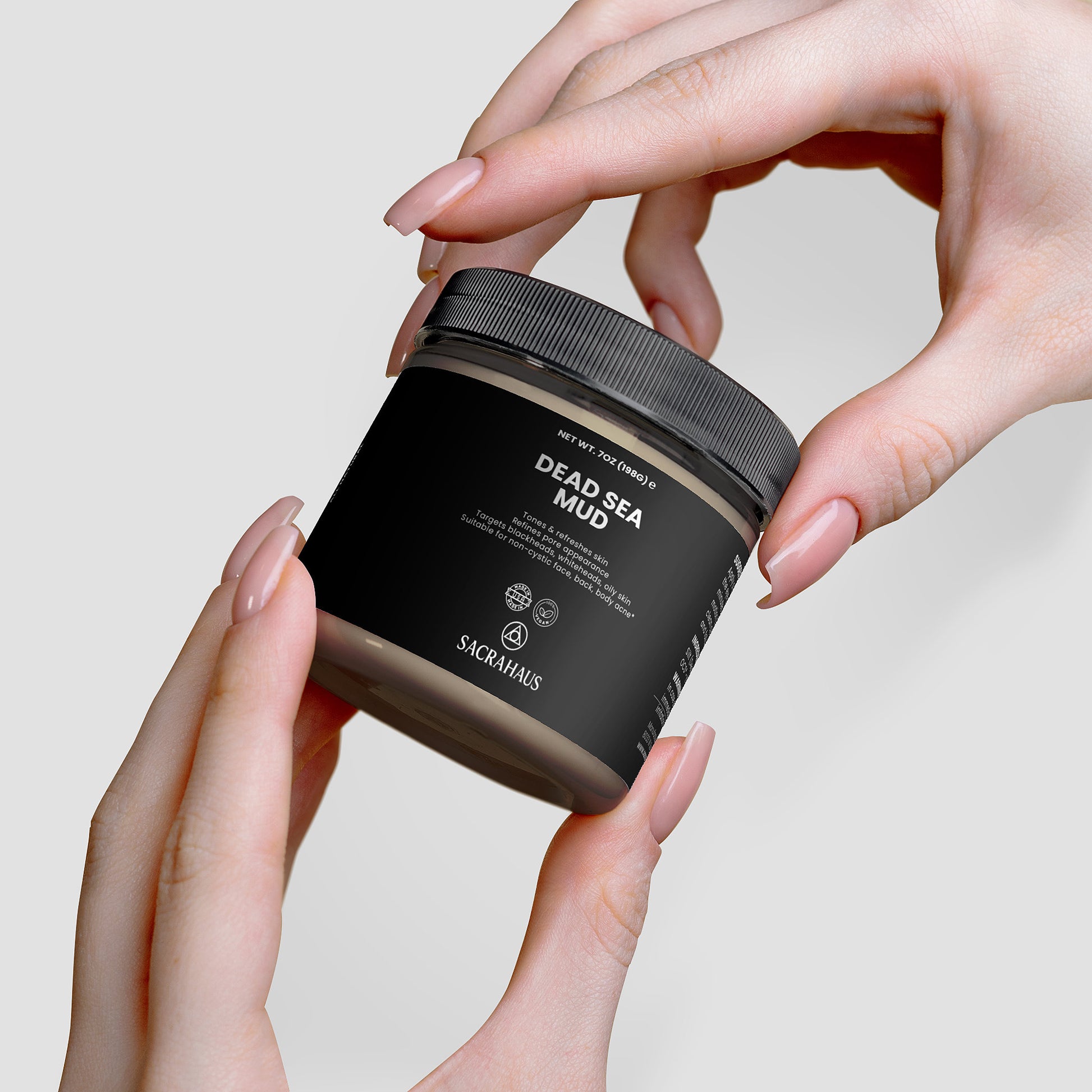 SACRAHAUS Dead Sea mud mask jar held by hands, perfect for rejuvenating skin care
