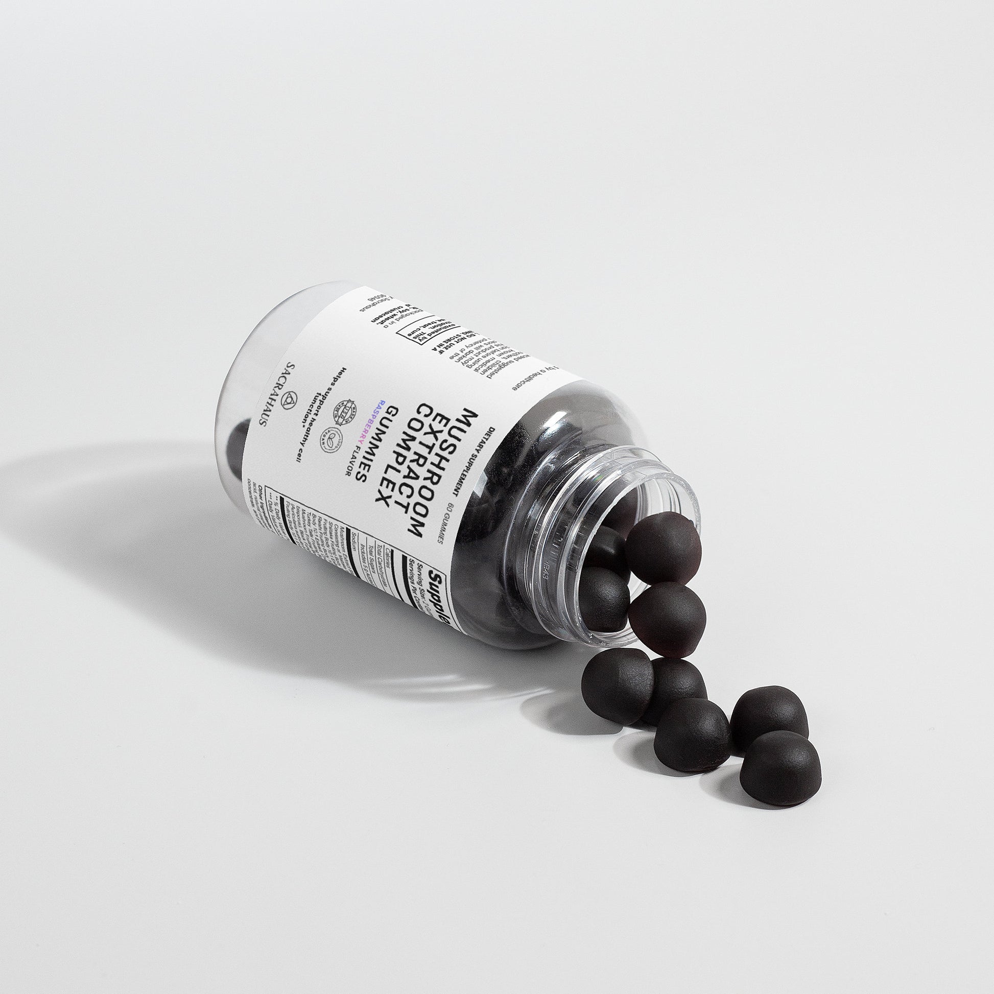 SACRAHAUS mushroom extract complex gummies in a bottle, some gummies spilled out on a white surface