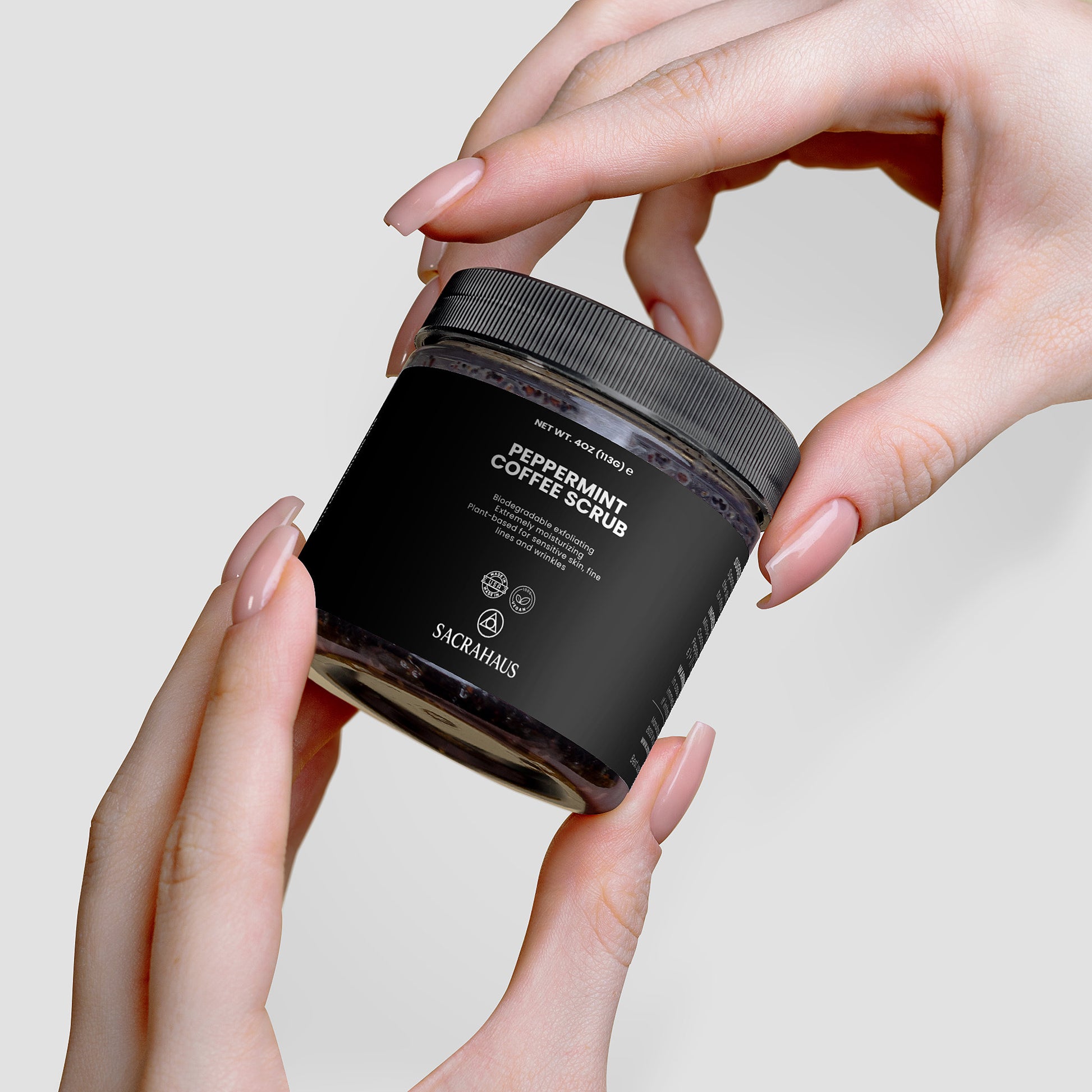 SACRAHAUS peppermint coffee scrub for sensitive skin in a stylish jar held by hands
