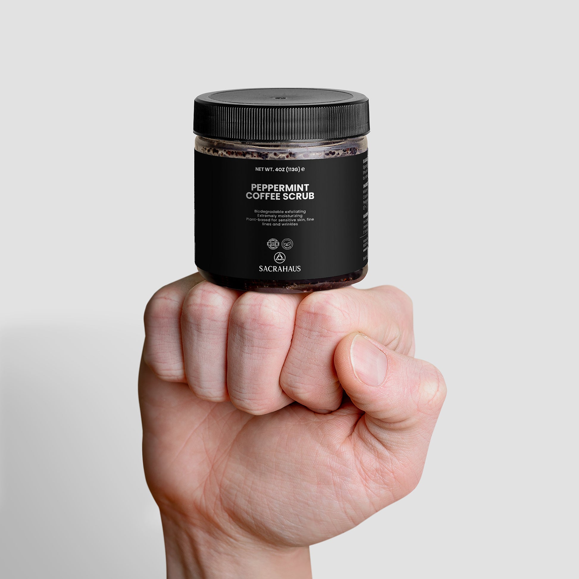 SACRAHAUS peppermint coffee scrub for sensitive skin in a jar held in a hand for skincare enthusiasts
