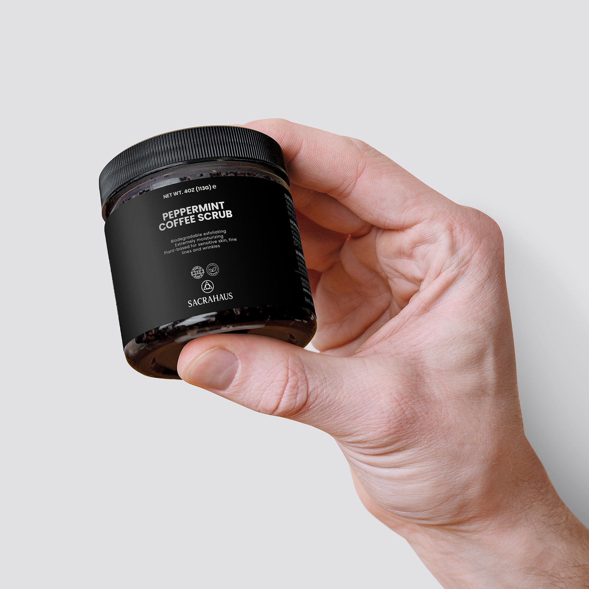 SACRAHAUS Peppermint Coffee Scrub for Sensitive Skin in a jar held by a hand