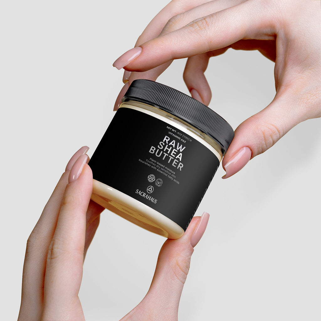 SACRAHAUS raw shea butter for skin in a sleek jar held between hands