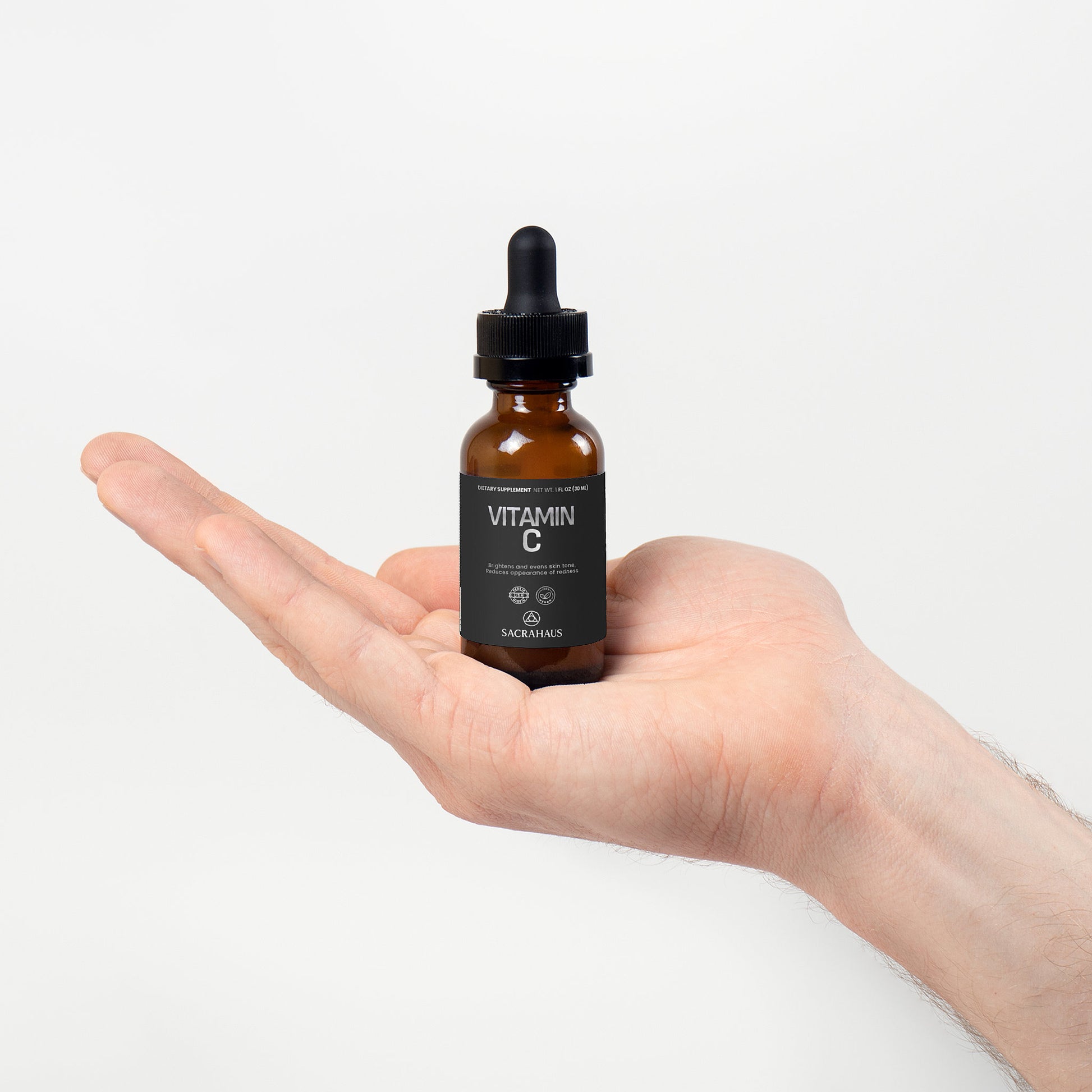 SACRAHAUS Vegan Vitamin C Serum in a dropper bottle held in a hand for facial care