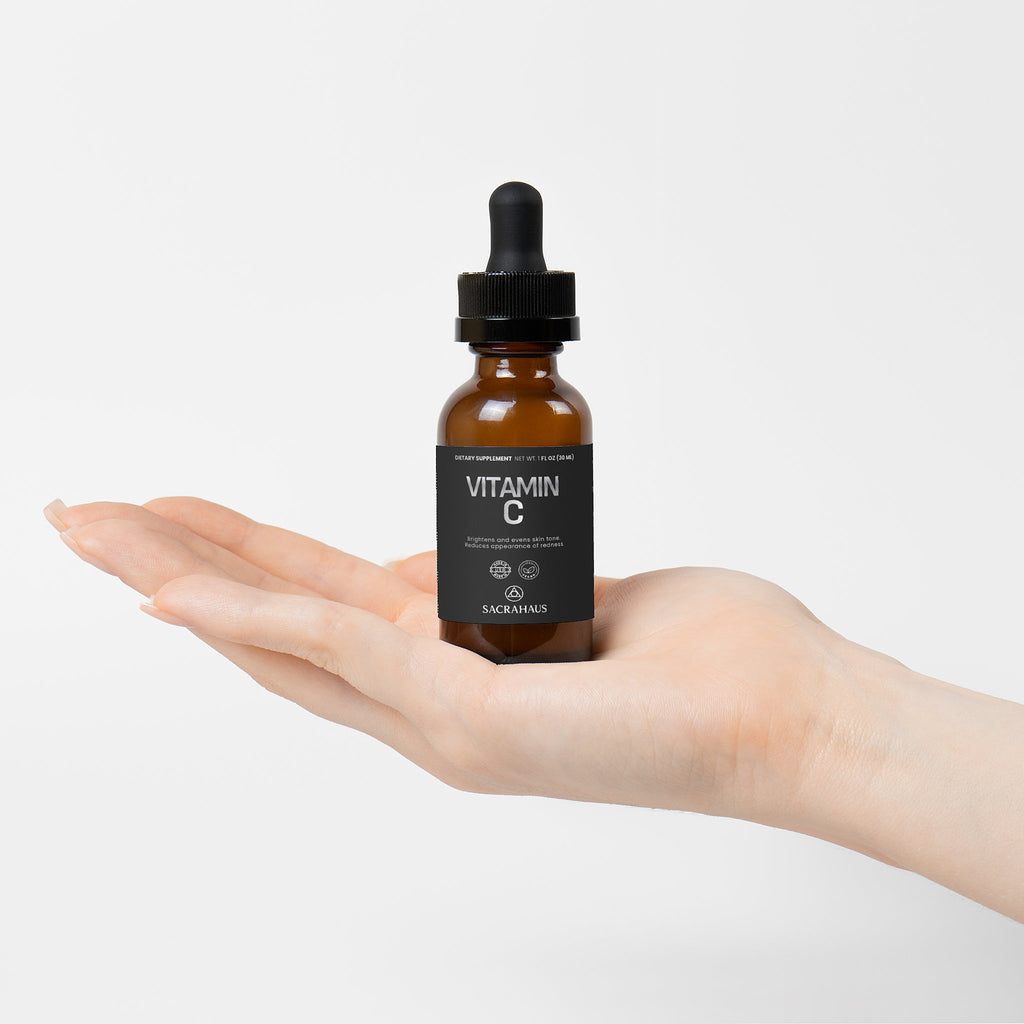 SACRAHAUS vegan vitamin C serum in a dropper bottle held in a hand for glowing skin