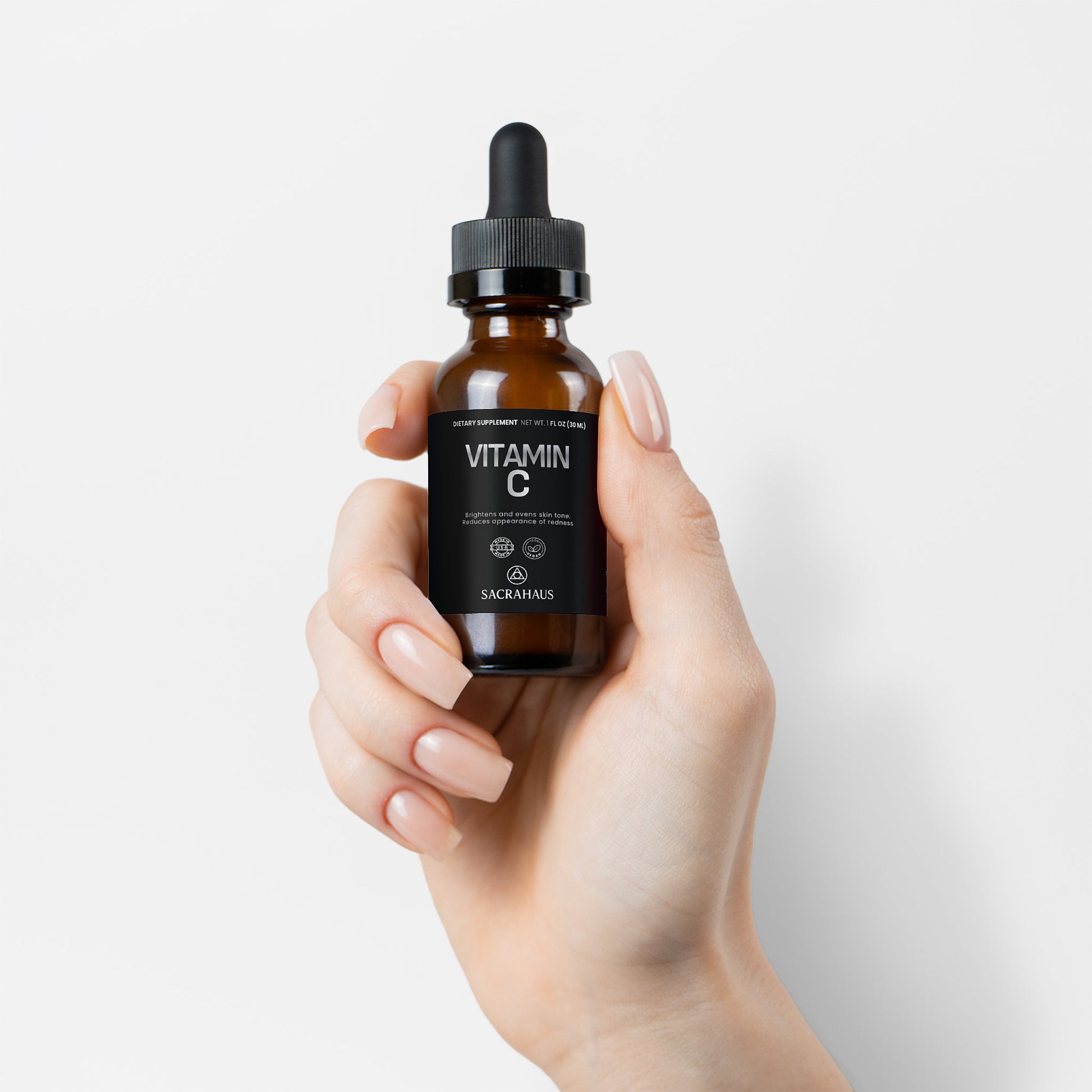 SACRAHAUS vegan vitamin C serum in a dropper bottle held in a hand for facial care