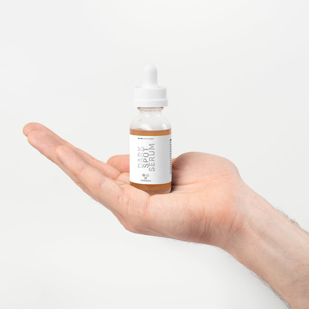 SACRAHAUS dark spot serum for sensitive skin in a dropper bottle held in a hand