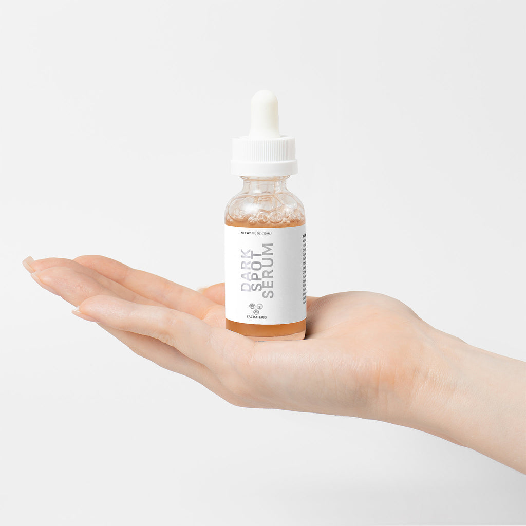 SACRAHAUS dark spot serum for sensitive skin in a dropper bottle held in a hand