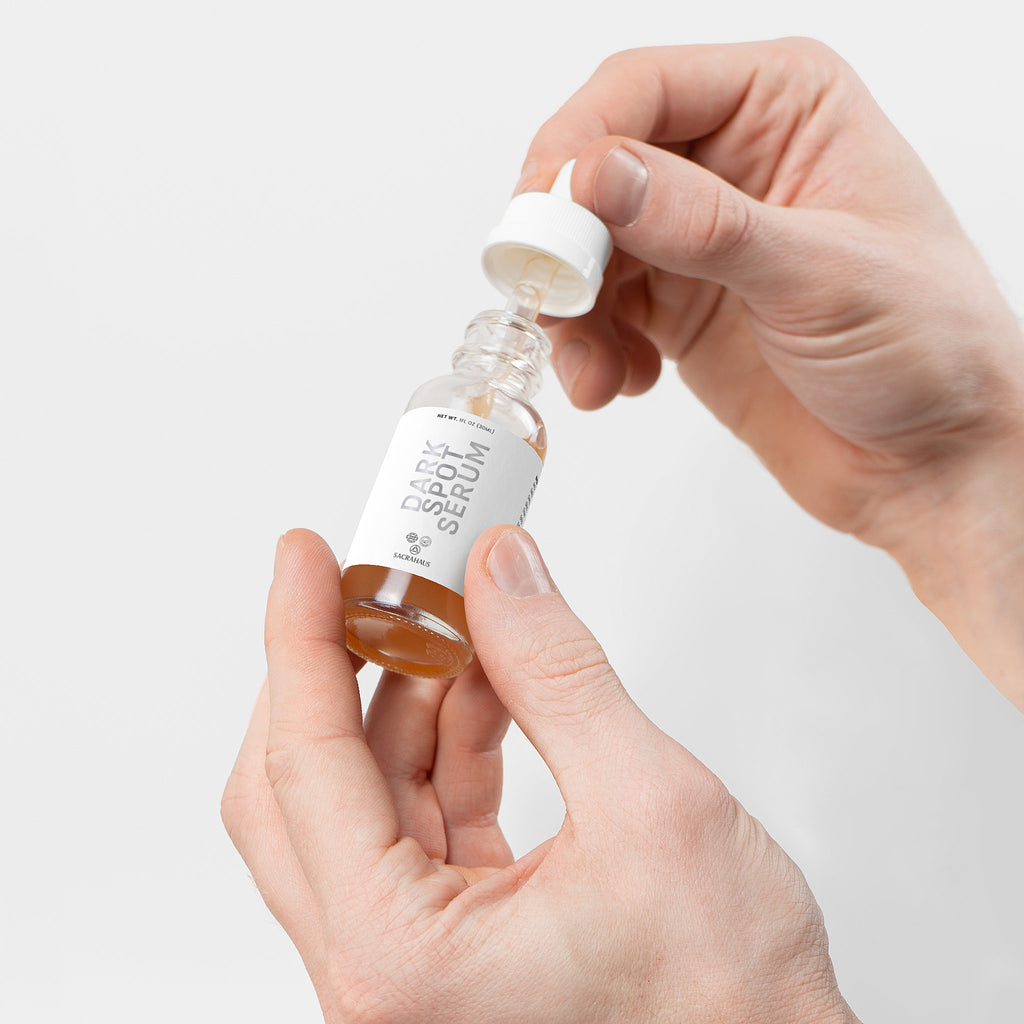 SACRAHAUS dark spot serum for sensitive skin in a dropper bottle held by hands